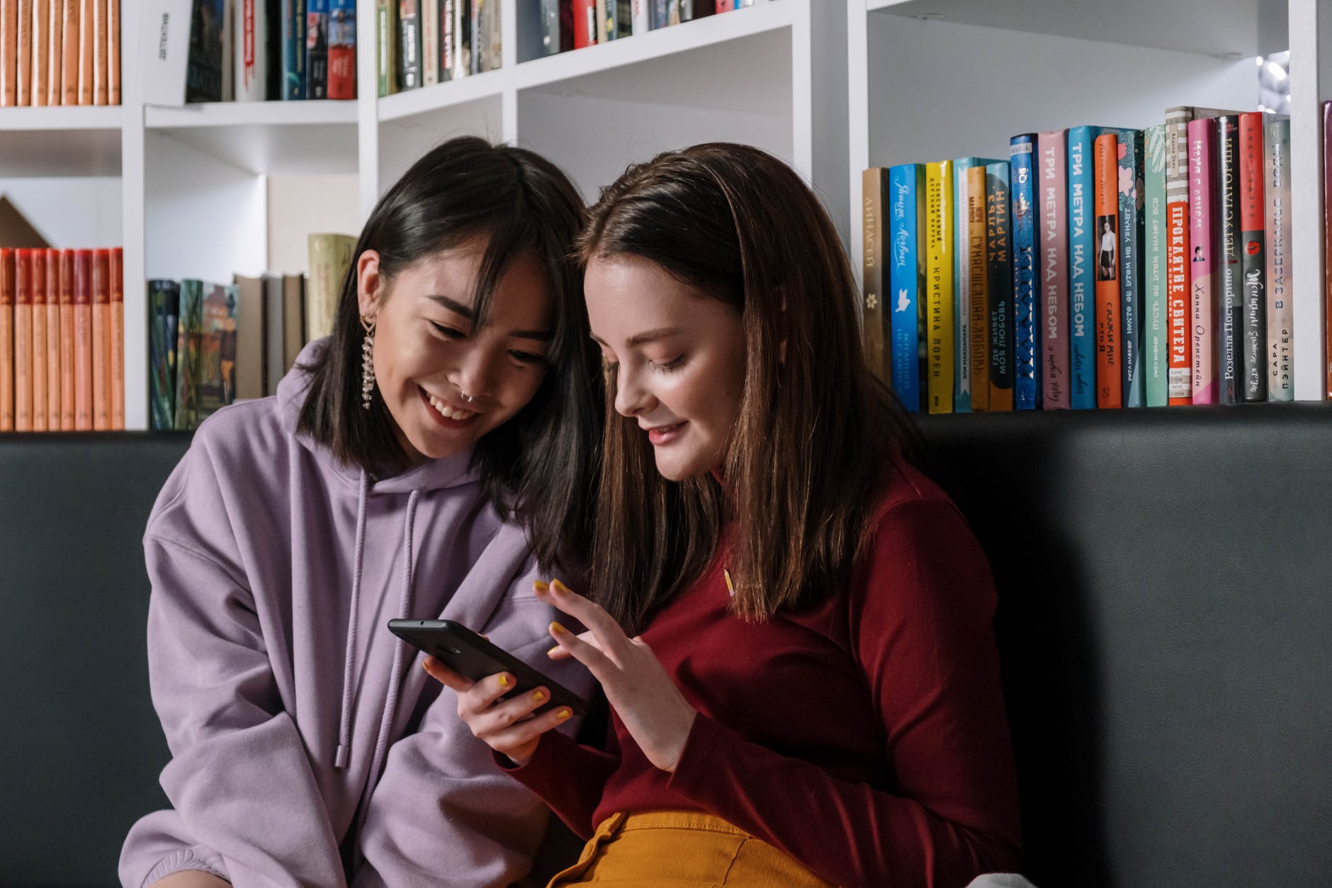 a girl in red sweater holding her phone while talking to her friend