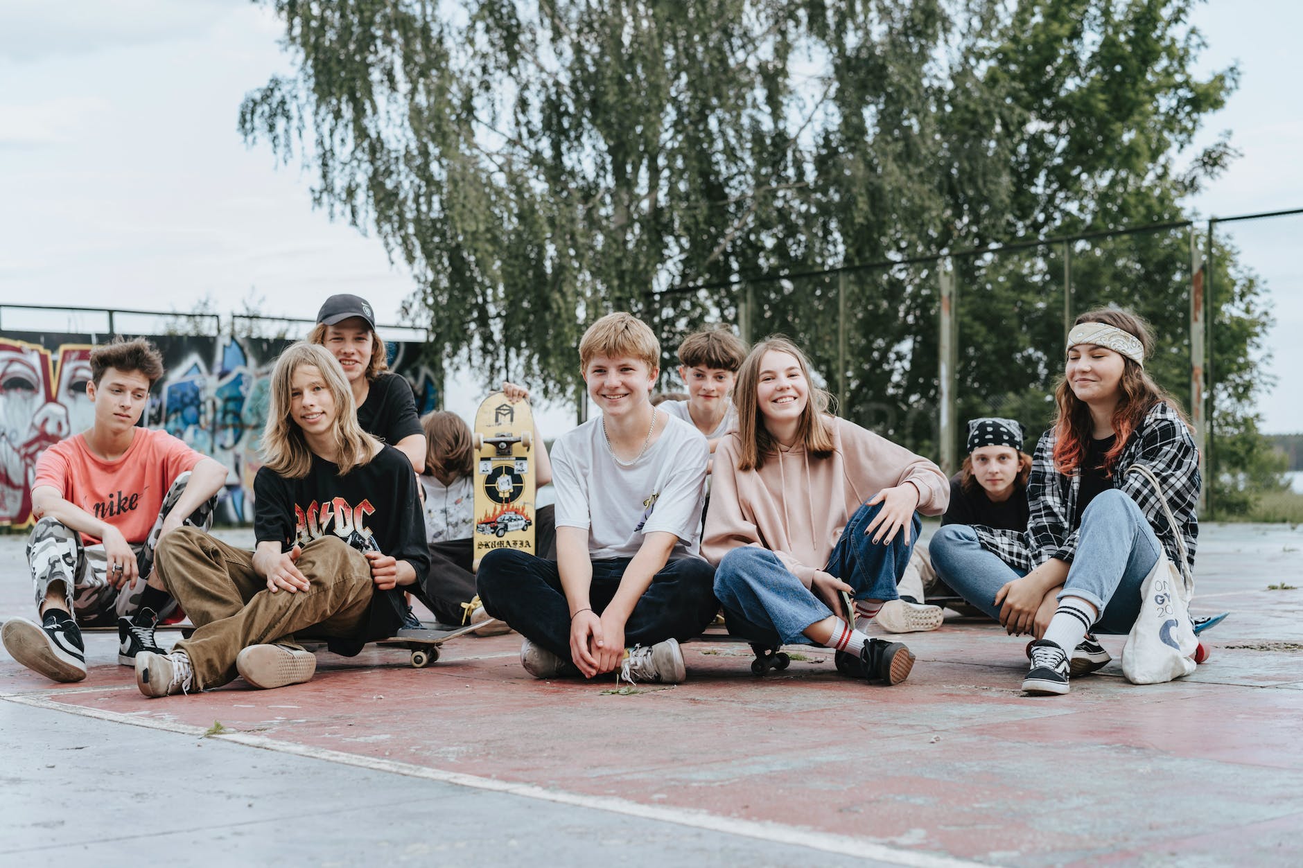 group of teenagers sitting on concrete pavement